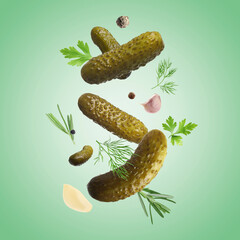 Tasty pickled cucumbers, herbs and spices falling on green background