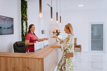 Beautiful blonde shakes hands with an employee of the dental office after the agreed dental...