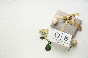 Cube calendar with date 8 MARCH, beautiful roses and gift box on white background. International Women's Day
