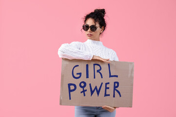 Beautiful young African-American woman holding paper with text GIRL POWER on pink background. Women...