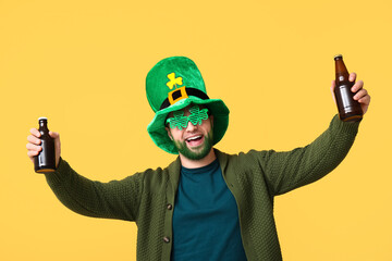 Happy young man in leprechaun hat and decorative glasses in shape of clover with green beard...