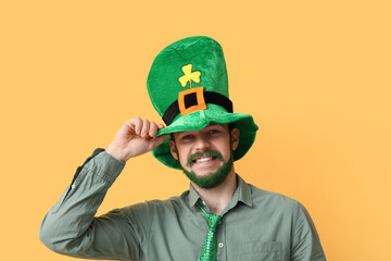 Young man in leprechaun hat with green beard on yellow background. St. Patrick's Day celebration