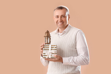 Muslim man with lantern and gift box for Ramadan on beige background