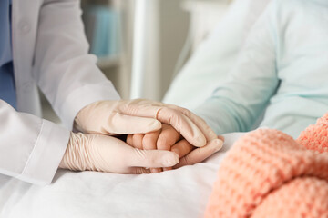 Little girl after chemotherapy with doctor holding hands in clinic, closeup. International...