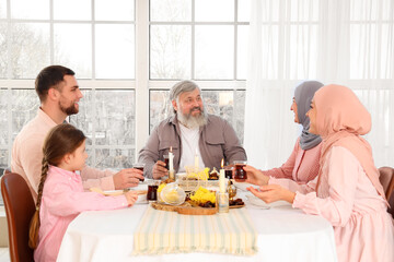 Mature Muslim man having family dinner at home. Ramadan celebration