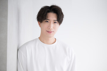 Handsome Asian man leaning against a wall, smiling and laughing