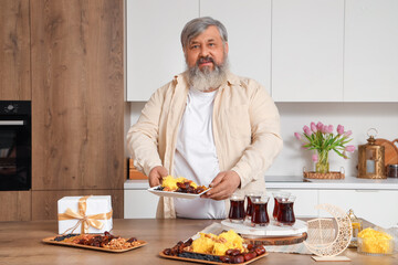 Mature Muslim man with traditional food celebrating Ramadan in kitchen