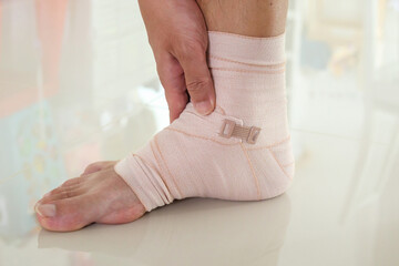 Man with ankle sprain elastic bandage for ankle injury and feeling pain