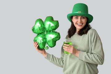 Beautiful young woman in leprechaun hat with air balloon in shape of clover and glass of beer on...