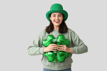 Beautiful young woman in leprechaun hat with air balloon in shape of clover and glass of beer on...