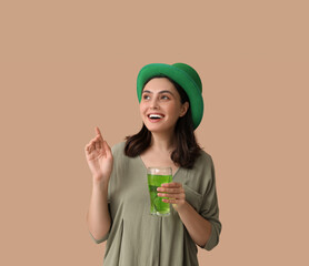 Beautiful young woman in leprechaun hat with glass of beer on brown background. St. Patrick's Day...