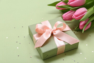 Gift box and bouquet of beautiful tulips on green background. International Women's Day