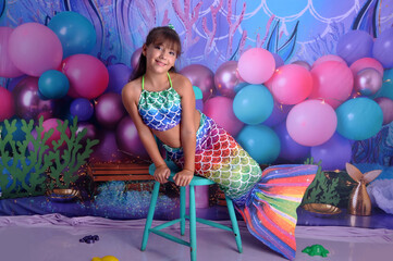 menina sorridente com roupa de sereia em cenário fundo do mar, ensaio de aniversário temático...