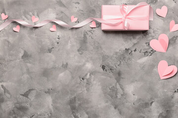 Composition with gift box, paper hearts and ribbon for Valentine's Day celebration on grey...