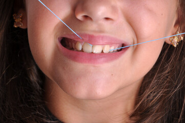 criança menina passando fio dental nos dentes, limpeza e higiene dental 