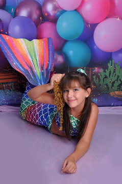menina sorridente com roupa de sereia em cenário fundo do mar, ensaio de aniversário temático sereia linda 