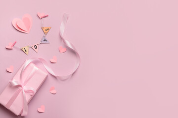 Composition with gift box, paper hearts and word LOVE for Valentine's Day celebration on beige background