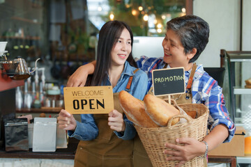 Cafe owner Retired elderly mother Carrying basket bread hugging beautiful Asian daughter small businessman employee barita waiter holding welcome opening both smiling each other promote family store