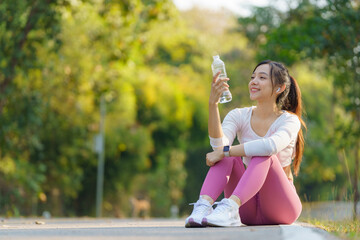 Tired runner woman with a bottle of water freshness after training outdoor workout at a public park.