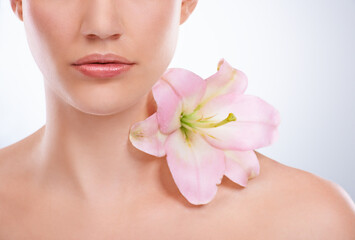 Closeup, woman and skincare with flowers, beauty and wellness on a white studio background. Half, person and model with natural cosmetics and grooming with treatment, shine and glow with dermatology