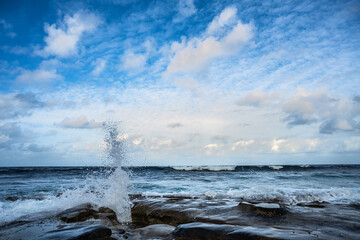 2023-12-31 THE LA JOLLA COASTLINE WITH WET ROCKS AND WAVES CRASHING AND SPLASHING WITH A NICE CLOUDY SKY IN LA JOLLA CALIFORNIA