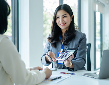 Asian business customer service representatives work and smile serve sell credit card to customers. choosing insurance plan in office