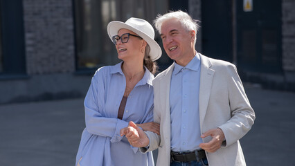 Stylish elderly laughing couple on a walk. Romantic relationships of mature people. 