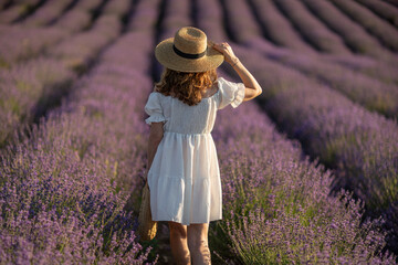 Back view woman lavender sunset. Happy woman in white dress holds lavender bouquet. Aromatherapy concept, lavender oil, photo session in lavender
