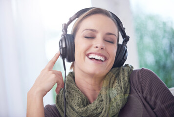 Home, funny and woman with headphones, listening to radio and peaceful with weekend break and calm. Apartment, laughing and person on sofa and headset for audio, sound and streaming music with humor