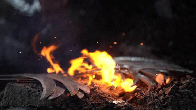 Iron is being burned to form a knife by a blacksmith in slow motion