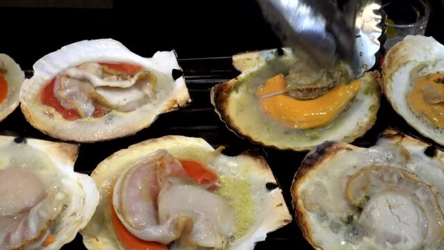 Grilling fresh seafood Japanese scallop hotate at fish market street food of Japan 4k