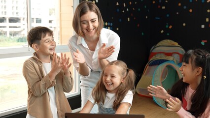 Caucasian teacher and happy students clapping hands to celebrate successful project writing...