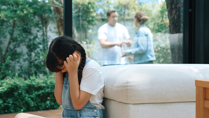 Stressed and unhappy young girl huddle in corner, cover her ears blocking sound of her parent...