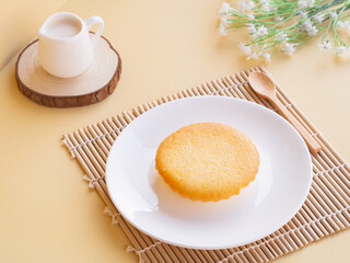 Fresh butter cake in white plate on beige background. Minimalist product concept