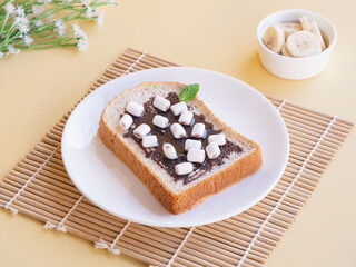 Toasts bread with marshmallow chocolate in white plate on beige background. Minimalist product concept