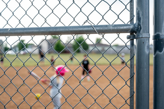 Defocused Parent view behind a chain link fence and home plate with a girl batter ready