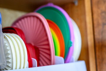 Narrow depth of field picture of an open kitchen cabinet with rows of organized storage of plastic...