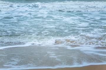 Beautiful turquoise sea with foamy water on the sandy shore. Resort and relaxation on vacation. Close-up. Space for text. Background. Front view.