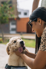 Woman caressing a tired puppy dog with tongue out outdoors