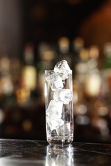 Whiskey and other long alcohol drinks glass filled with a lot of ice cubes and prepared to pour the...