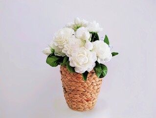 Pictured are white plastic flowers with green leaves called jasmine flowers in a brown basket. They are fragrant and are used as a symbol of Mother's Day in Thailand.