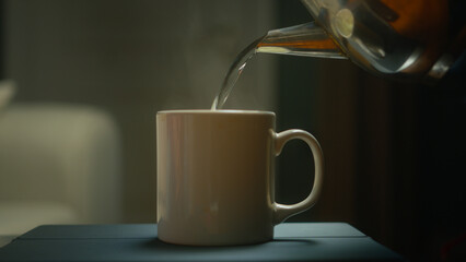 Close-up of hot water pouring from a teapot into a white cup
