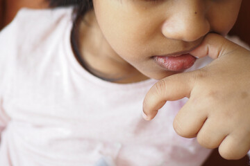  child girl biting her nails at home,