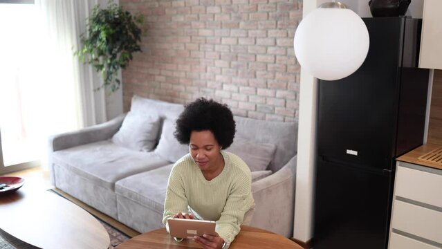 African American woman using tablet and setting up smart system at her home