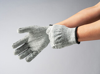 Male hand wearing knife-proof gloves on gray background.