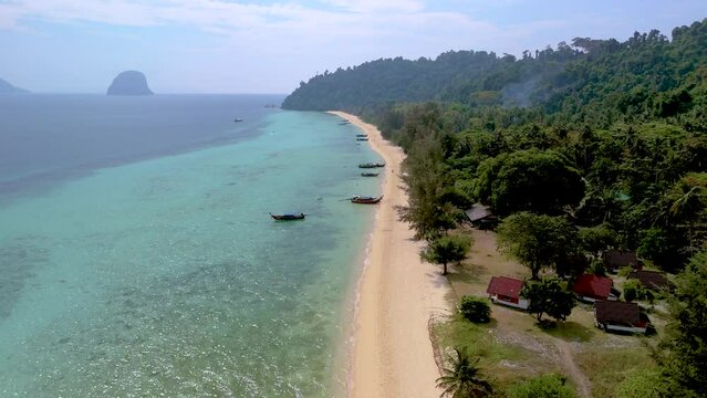 Drone aerial view at Koh Ngai tropical island with longtail boats and soft white sand, and a colored ocean in Koh Ngai Trang Thailand