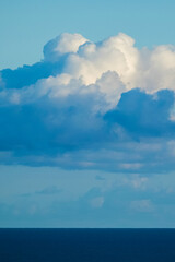 Beautiful blue coloured background of sea ocean water and horizon line with white clouds in the sky - concept of travel and nature