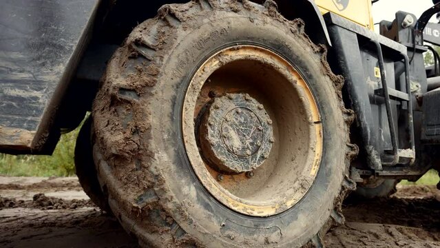 tractor riding on ground on construction site in modern cottage complex, details view of wheels