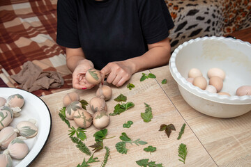 A girl cooks eggs in tights with leaves. Easter