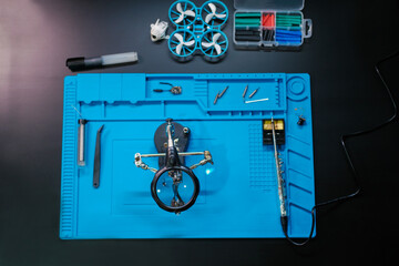 Top view of a workbench containing tools for repairing the video transmitter board of an FPV drone....
